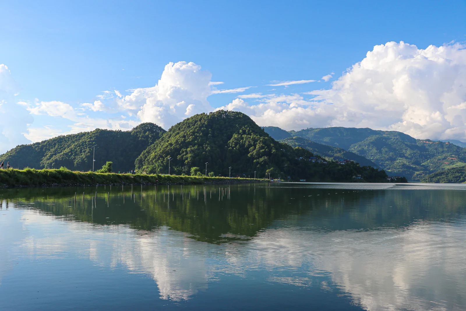 Green hills and clouds reflected in Begnas Lake.